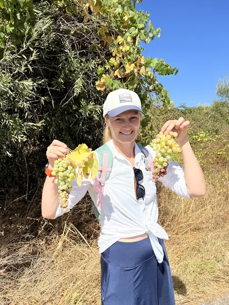 Original photo of a smiling woman holding grapes outdoors